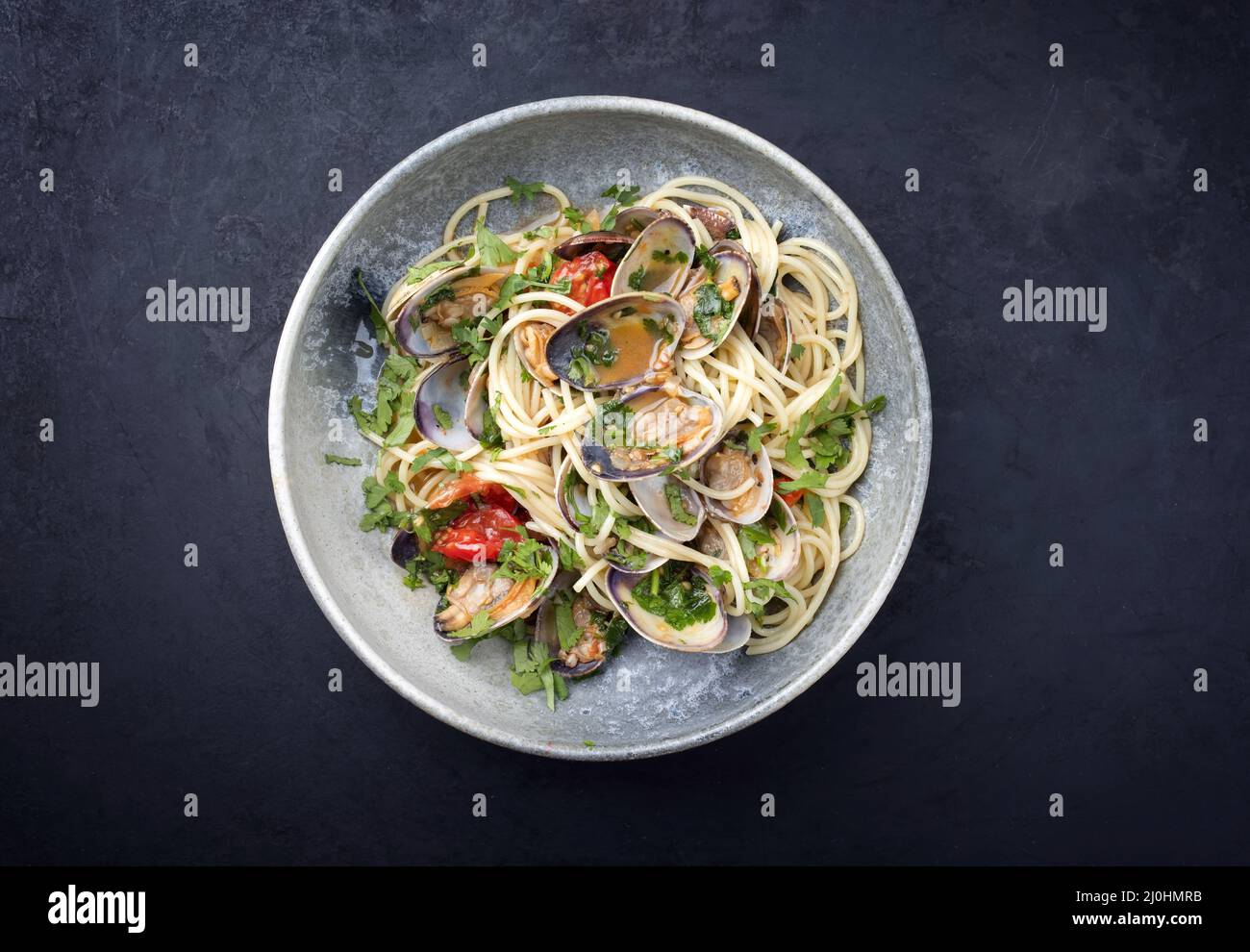 Spaghetti alle vongole with tomato in seafood jus served as top view at a Nordic design bowl with copy space Stock Photo