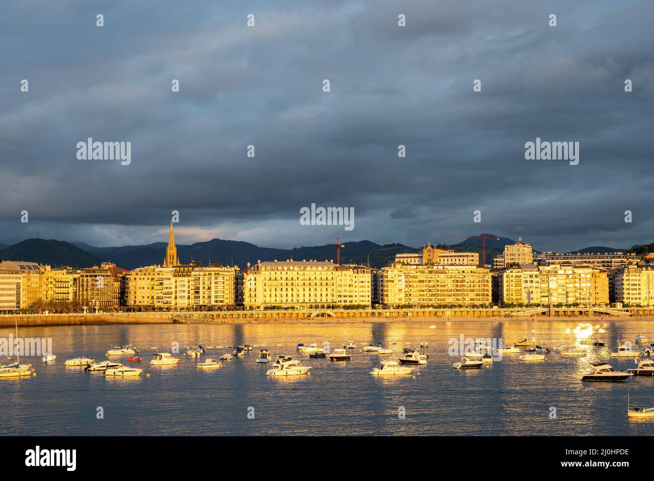 The buildings along Playa de la Concha in San Sebastian, Spain, illuminated by the last rays of the Stock Photo