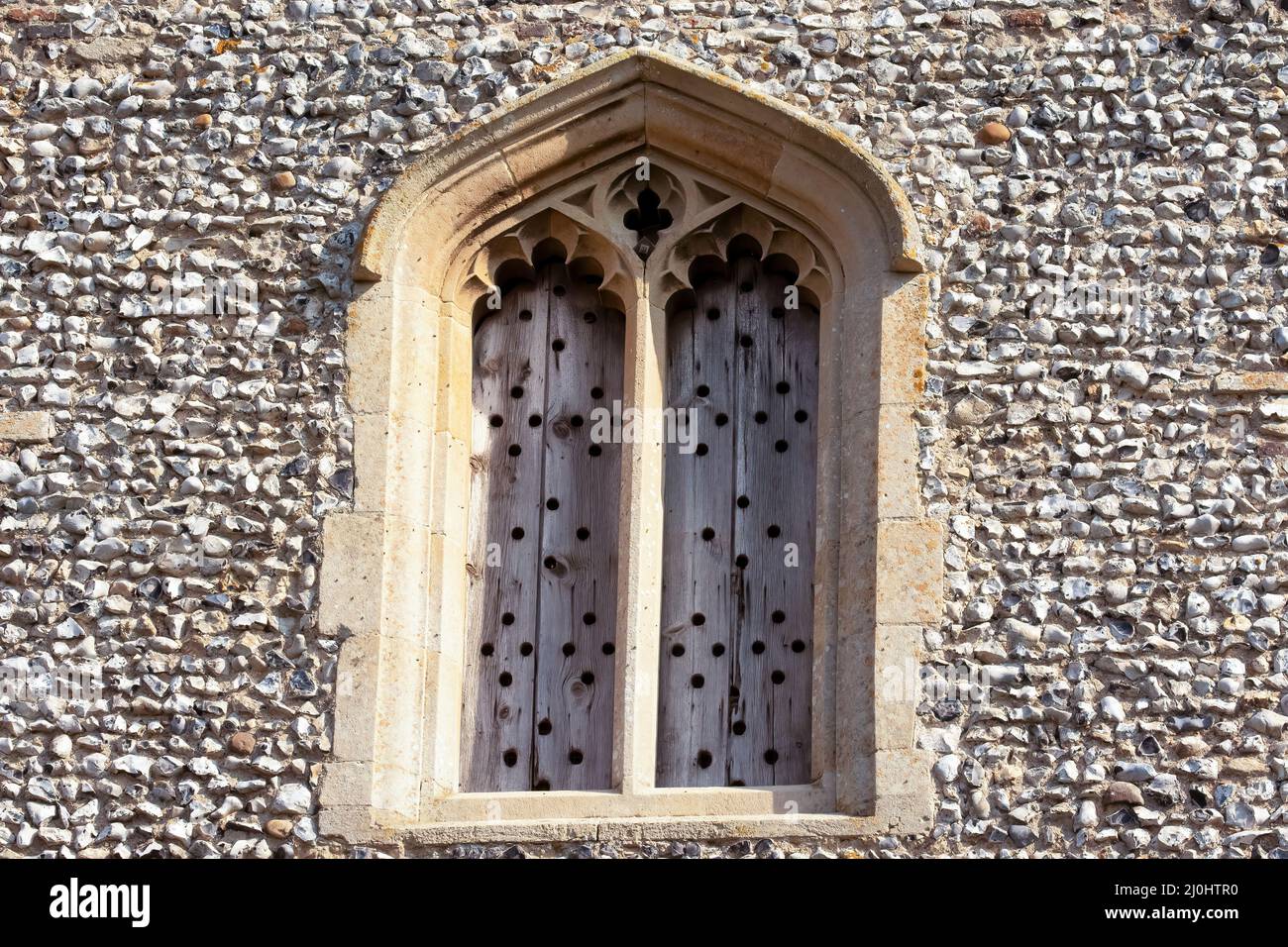 Historic arch window with old wooden shutters set in flintstone wall Stock Photo Alamy