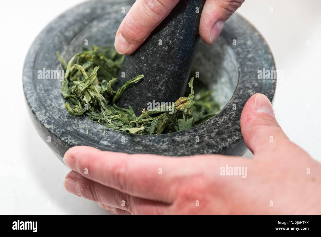 Finely pound the dried wild garlic in a mortar - herbs Stock Photo