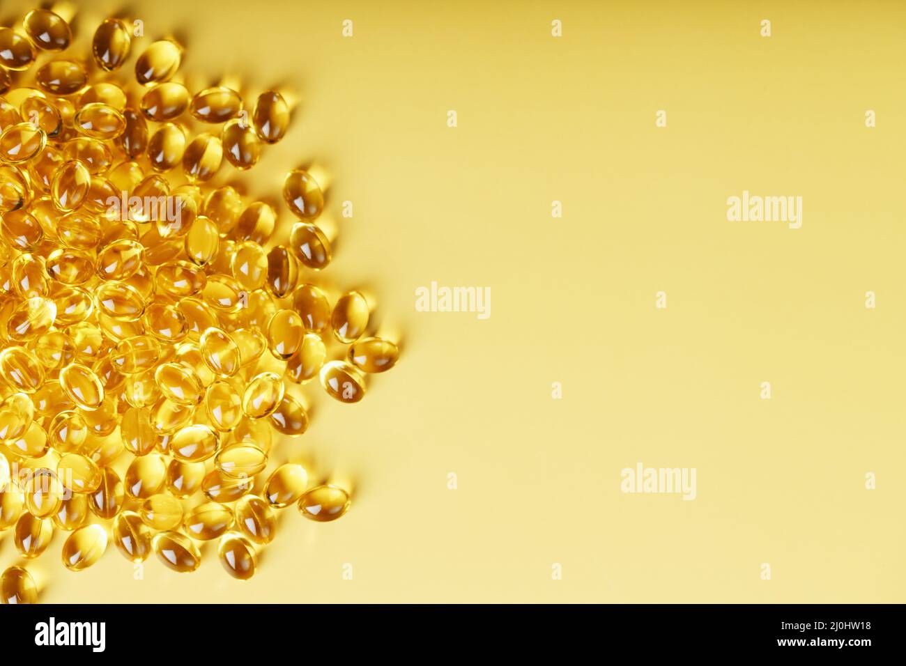 The texture of the capsules in the shell with liquid vitamin D3 in full screen. Gold capsules with a dietary supplement for joints teeth and bones. Stock Photo