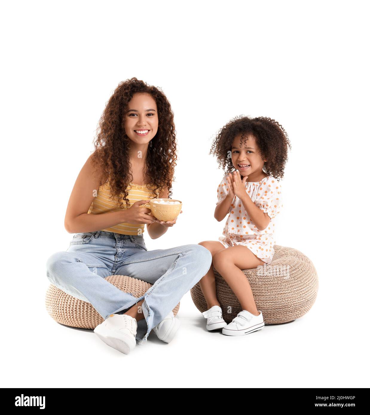 Little African-American girl and her mother with cup of sweet cocoa on white background Stock Photo