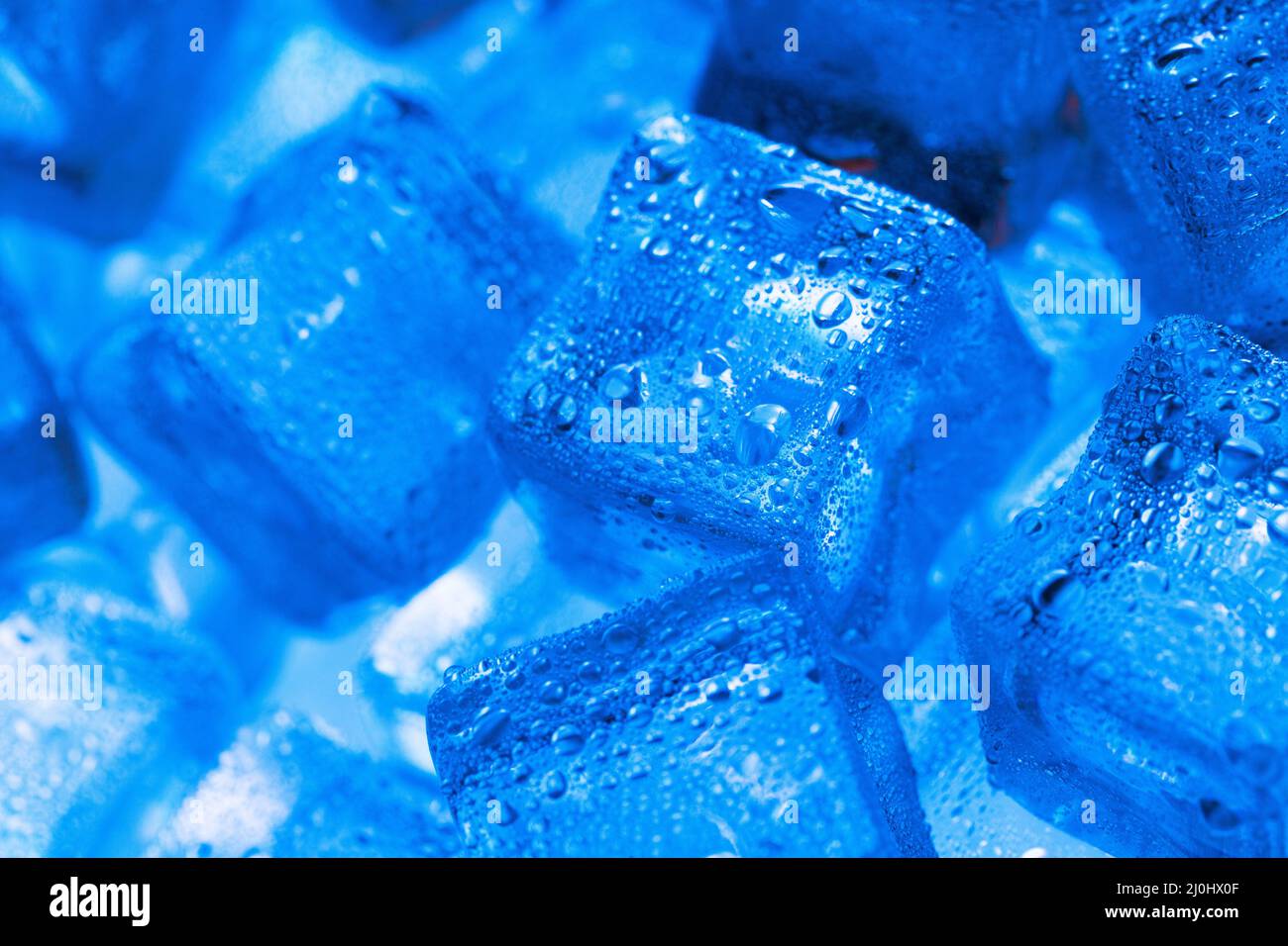 Ice made of cubes lined up with drops on a blue background Stock Photo