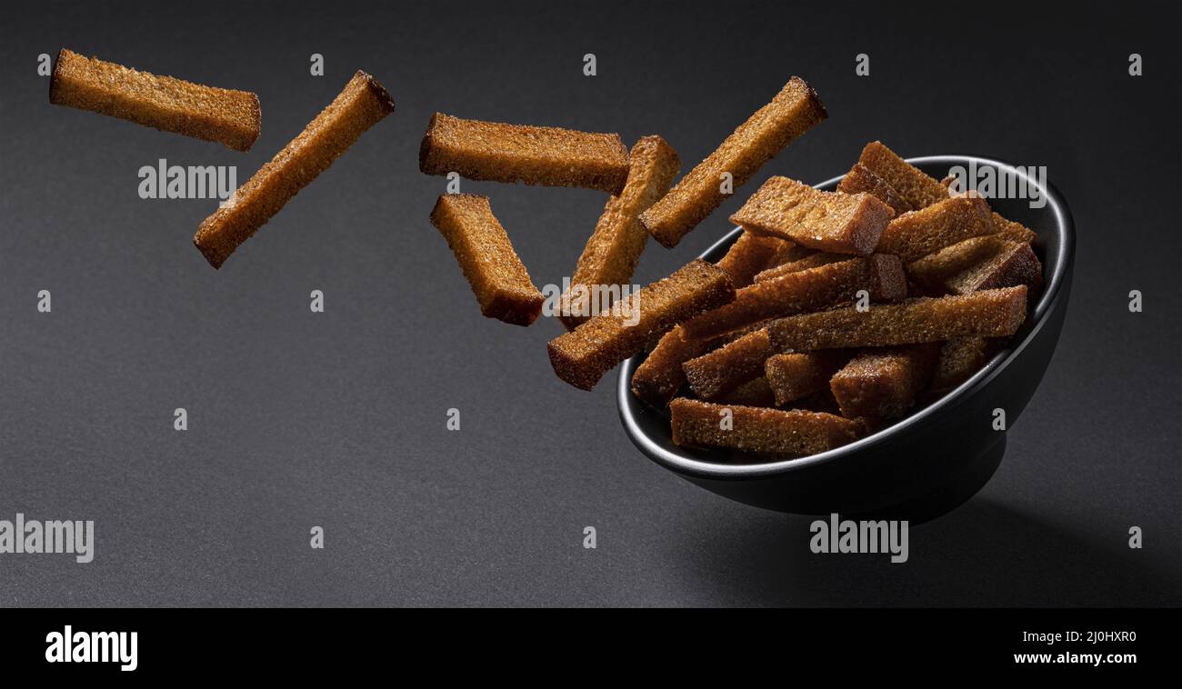 Falling rye croutons on black background Stock Photo