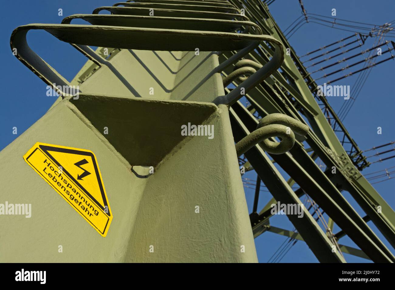 Electricity pylon with warning notice (in German) Stock Photo