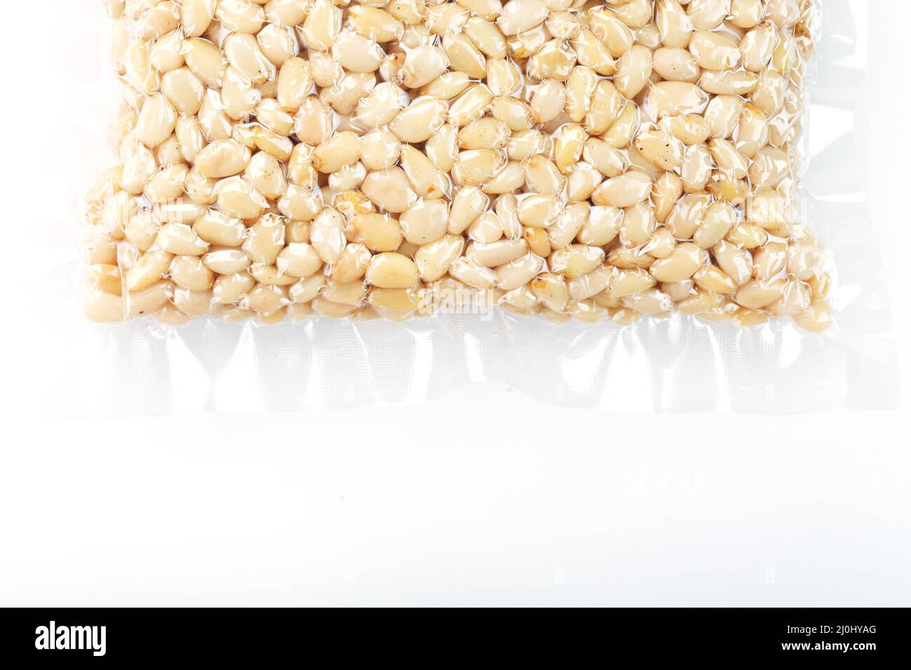 Pine nuts in a transparent vacuum package over a white background Stock Photo