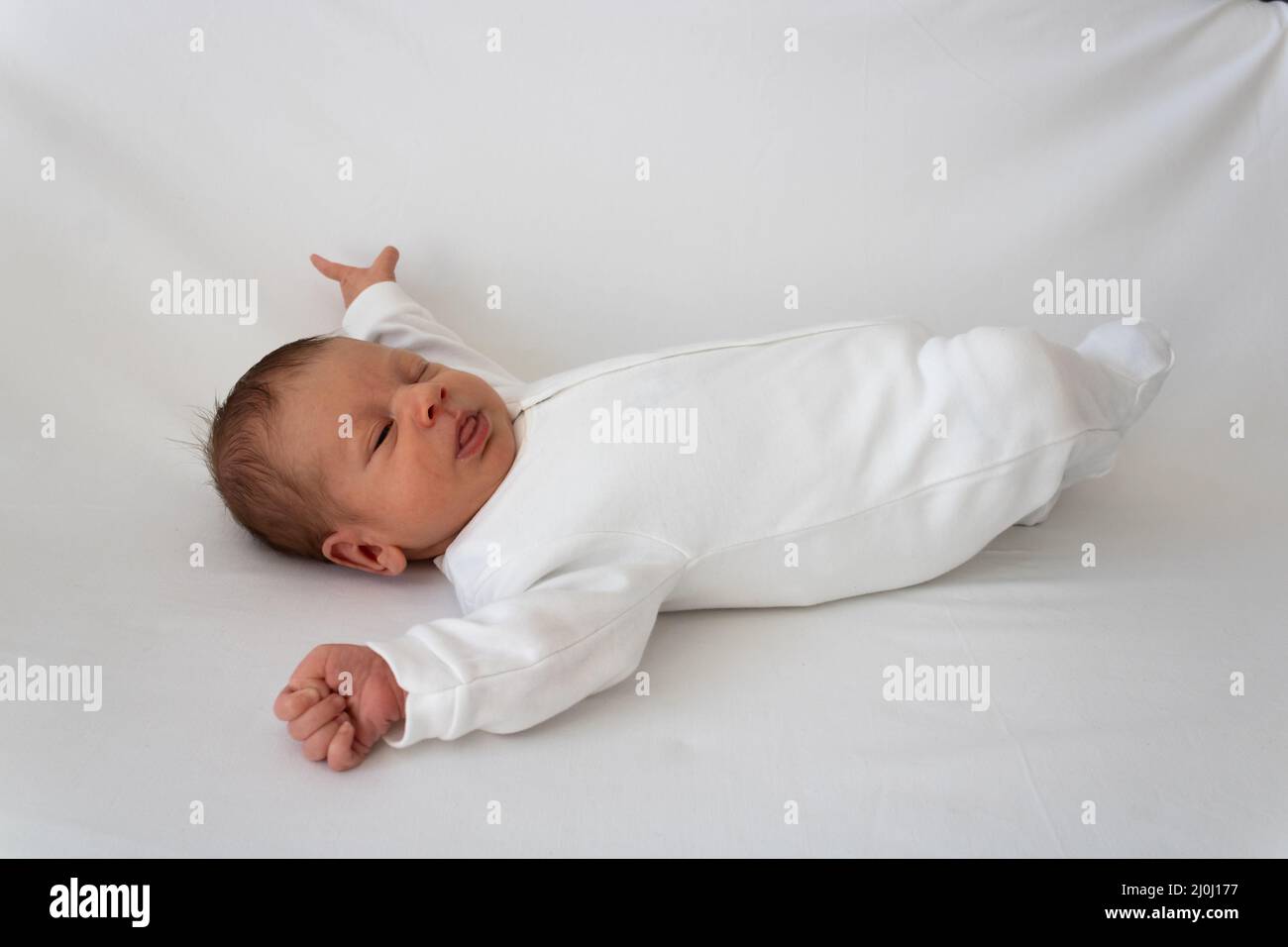 Newborn baby in a white clothes on a white blanket Stock Photo - Alamy