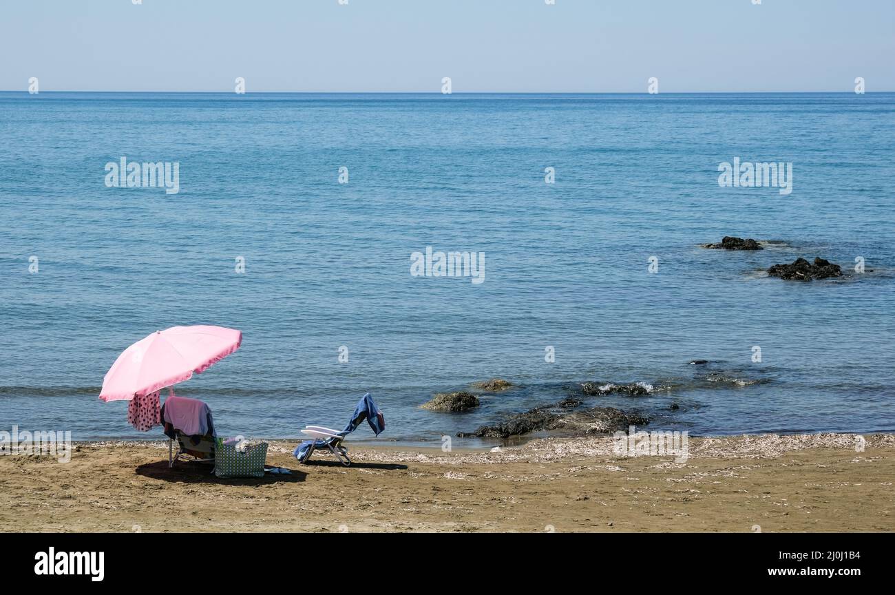 Beach umbrella and relaxing chair on a sandy coast in summer. Summertime holidays Stock Photo