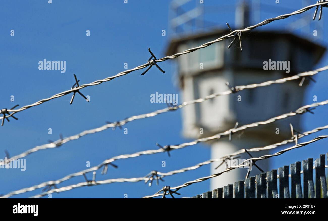 Barbed wire with a watchtower in the background Stock Photo