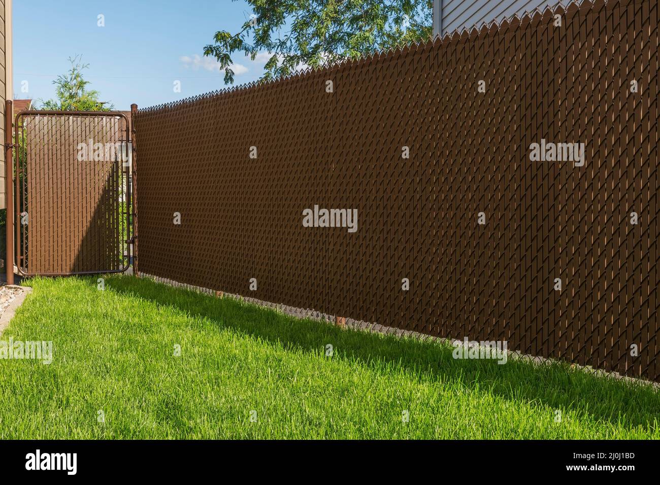 Brown chainlink fence with privacy slats in residential backyard Stock