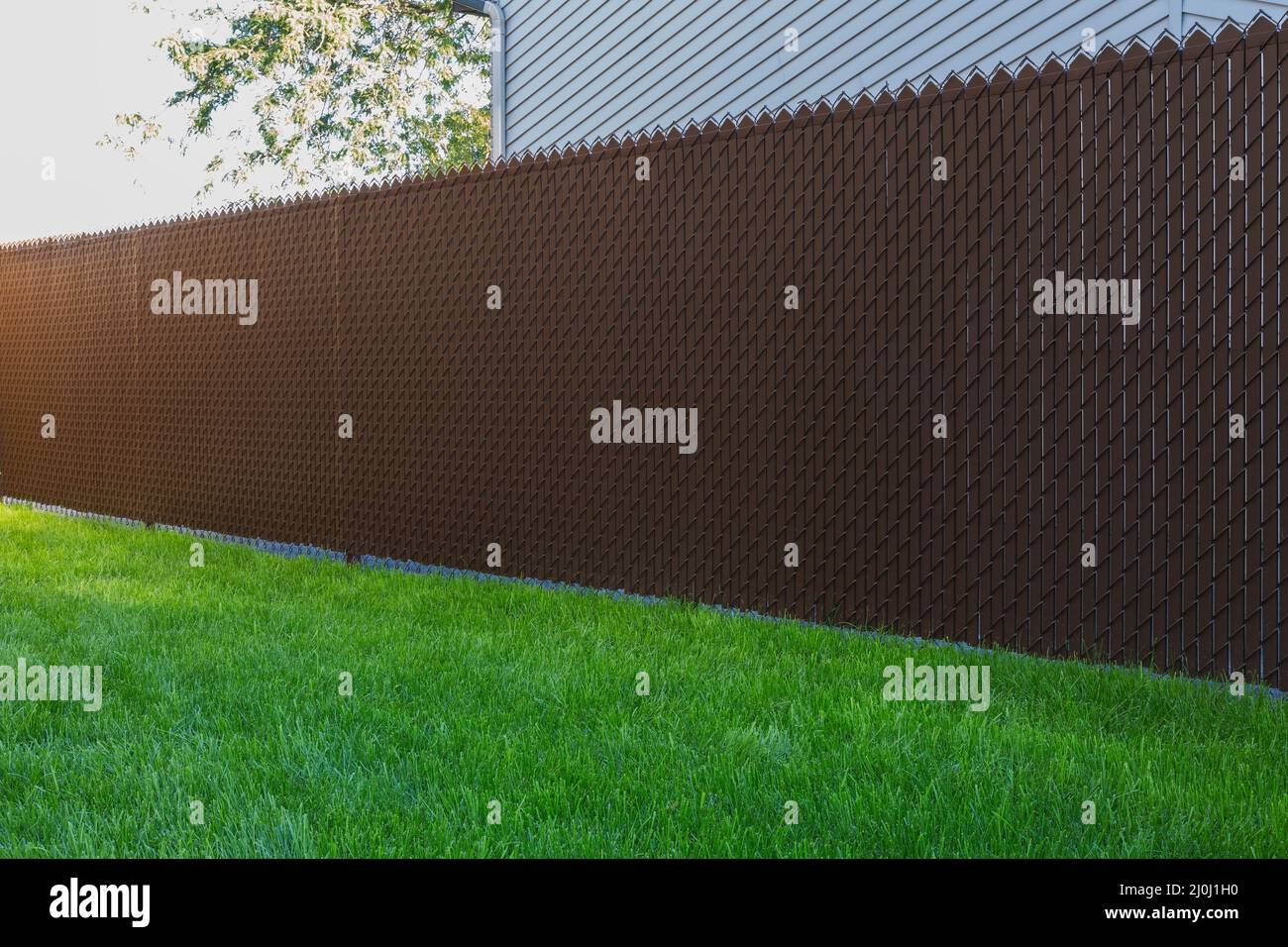 Brown chainlink fence with privacy slats in residential backyard Stock