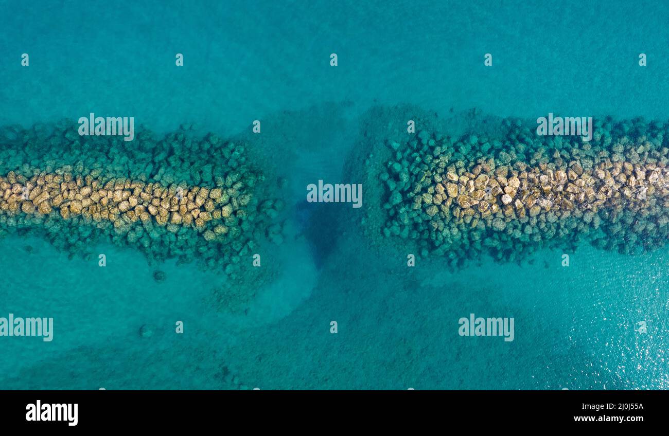 Aerial view from flying drone of crystal blue ocean water and sea wall ...