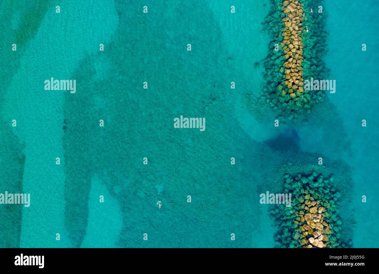 Aerial view from flying drone of crystal blue ocean water and sea wall ...