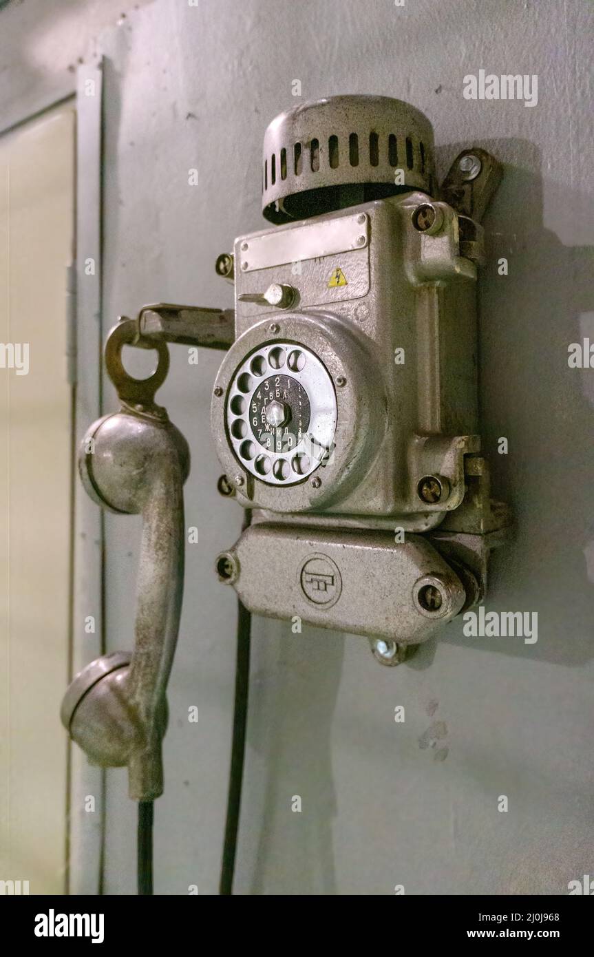 Old vintage wired telephone for communication hangs on textured gray