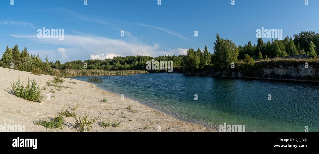 Landscape of limestone mountains and calm blue groundwater lake in an old quarry Stock Photo