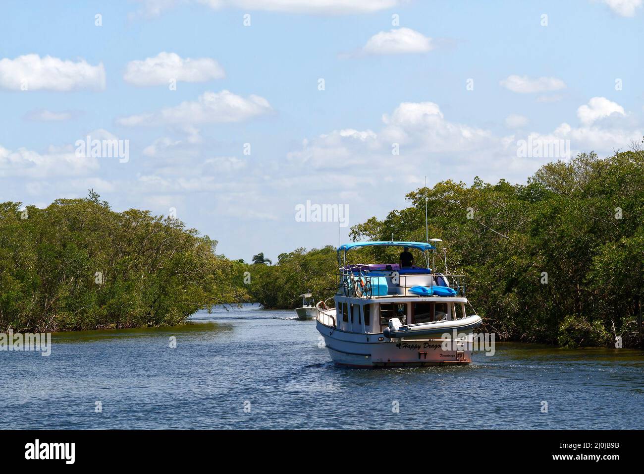 2 motor boats passing, trawler, mangroves, blue water, canal scene