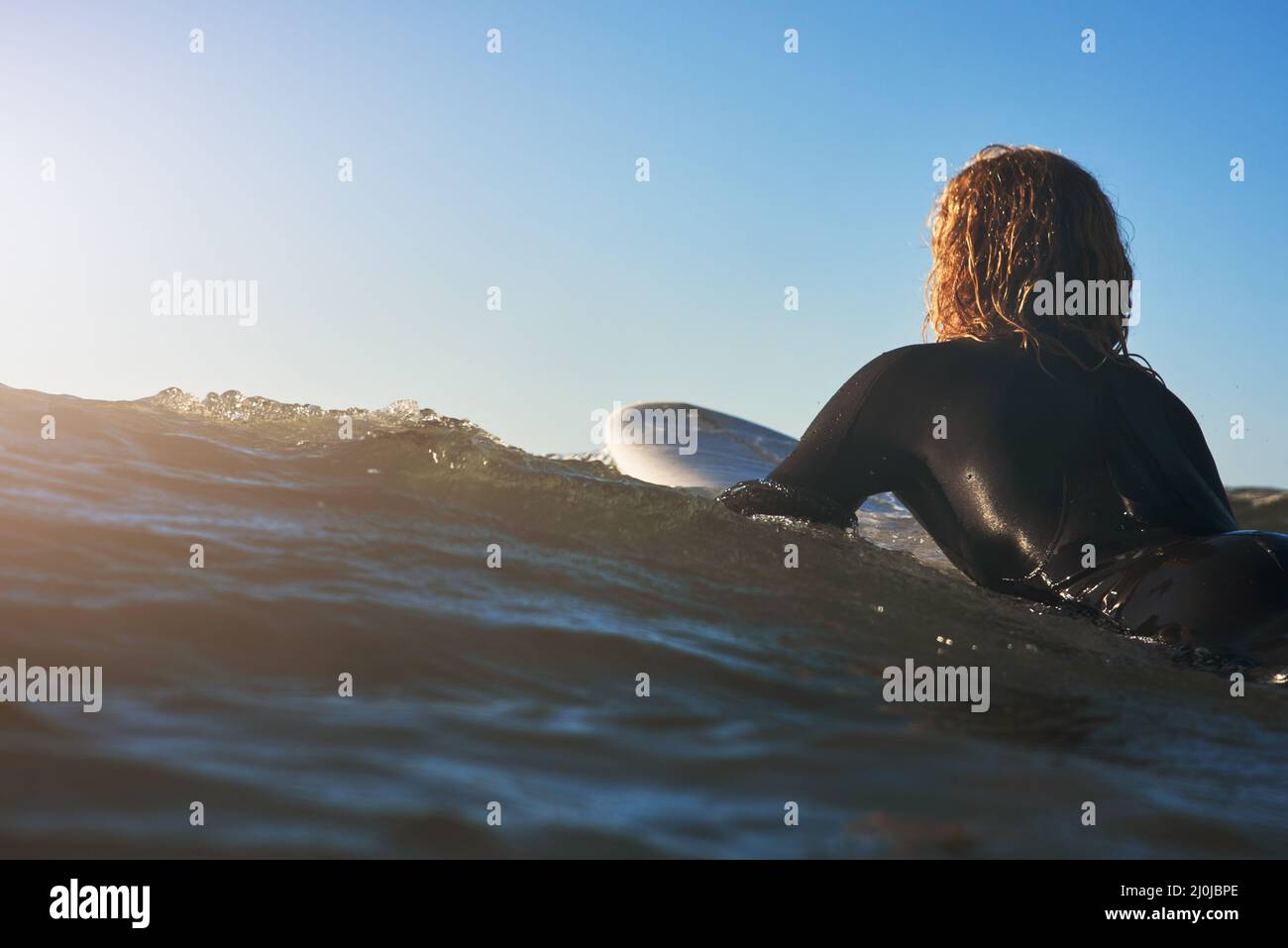 Riding the waves of life. Rearview shot of a young man surfing in the ocean. Stock Photo
