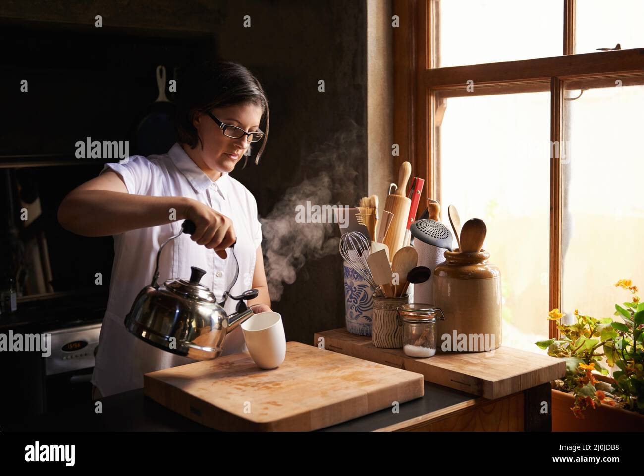 The best thing after a long day. Shot of an attractive young woman making a cup of tea in her kitchen. Stock Photo