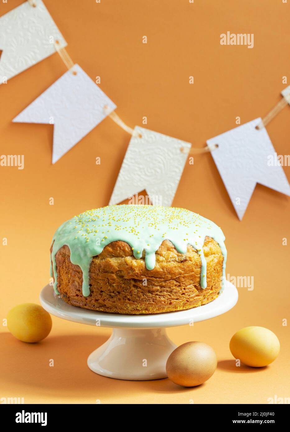 Easter cake covered with icing on a cake bowl and Easter eggs. Festive concept. Stock Photo