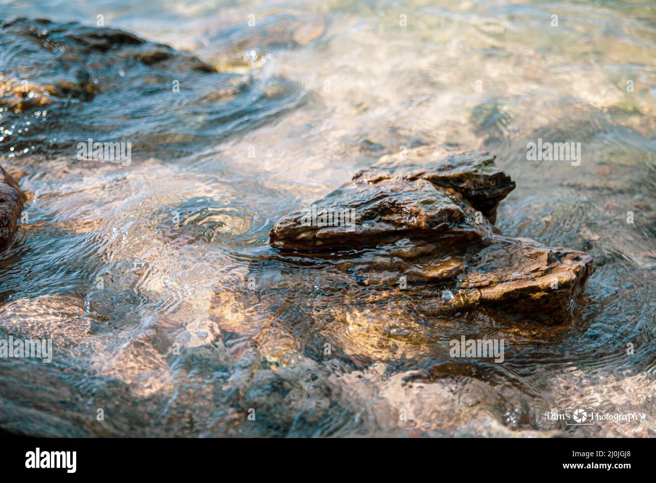 Closeup shot of rocks surrounded by sea foam on a coast Stock Photo - Alamy