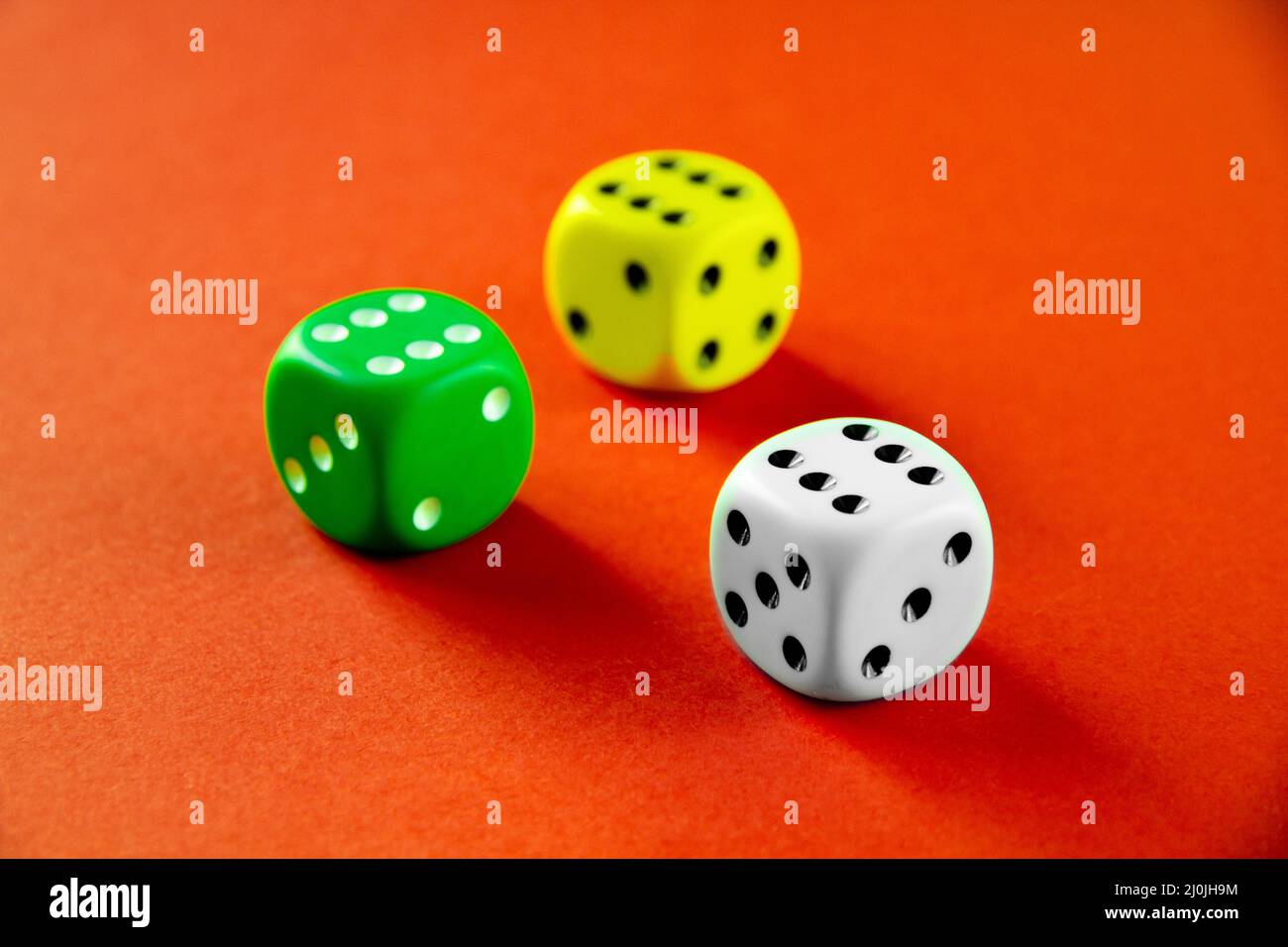 Three colorful dices isolated on orange background Stock Photo