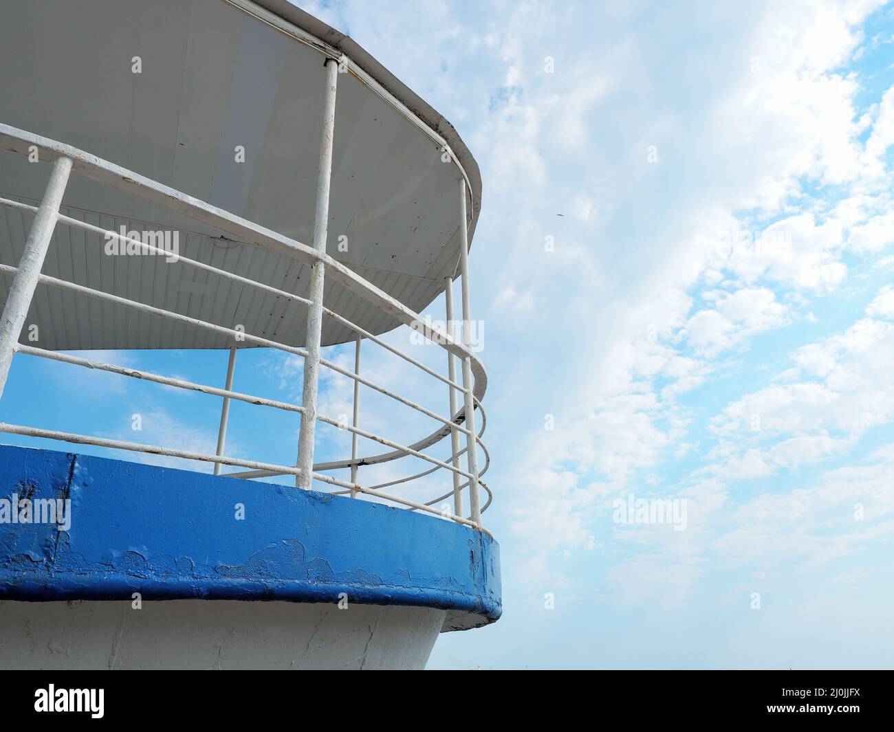 Fragment of an old iron ship with peeling paint against a blue sky with clouds Stock Photo