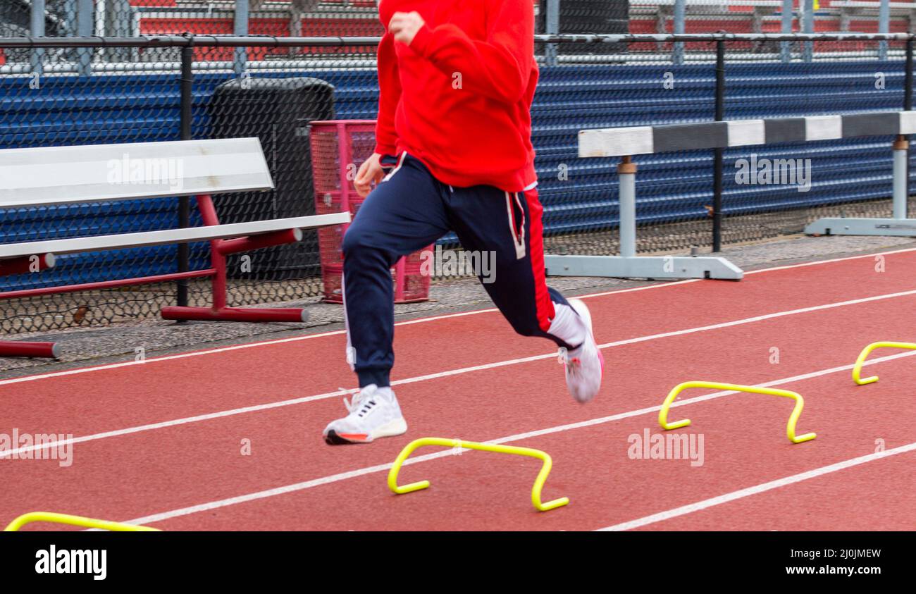 A high school track runner is running the wicket drill by running over