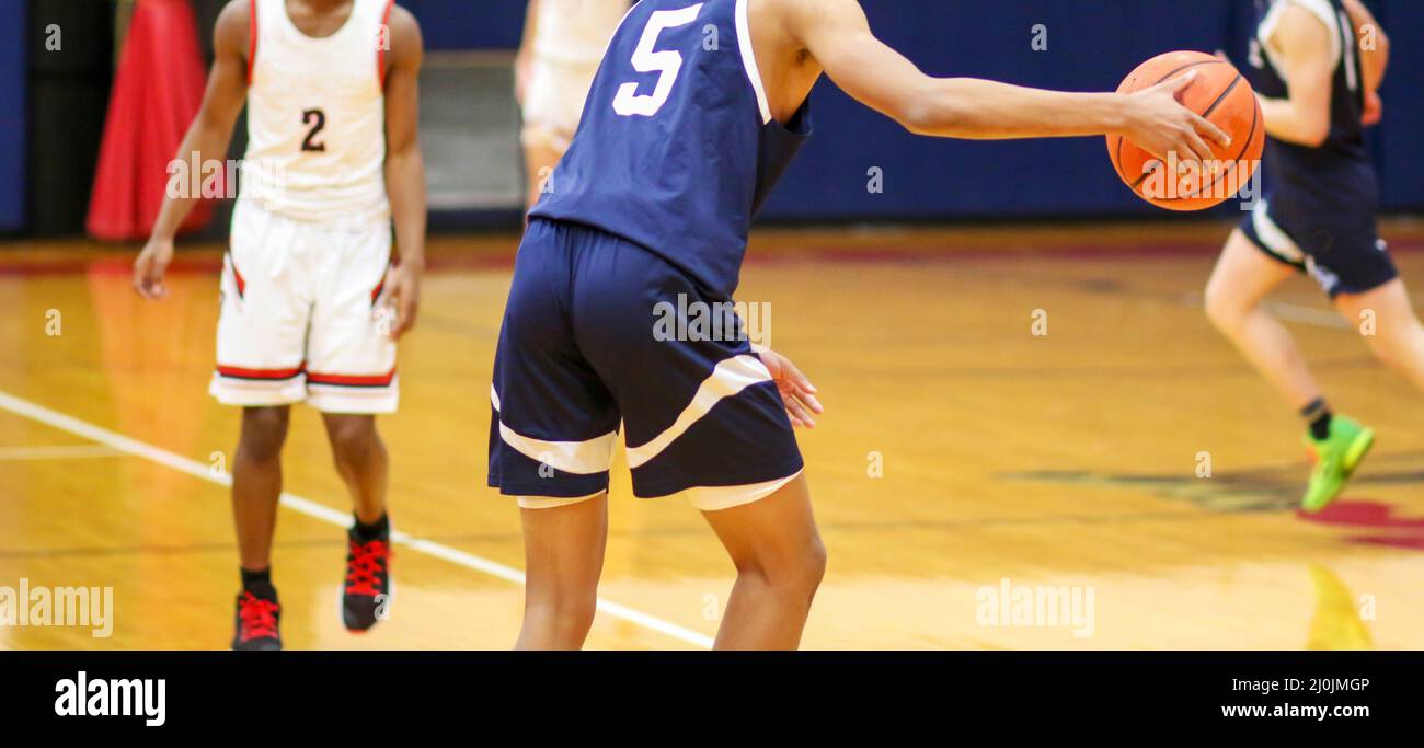 High school basketball player dribbling the ball upcourt druing a