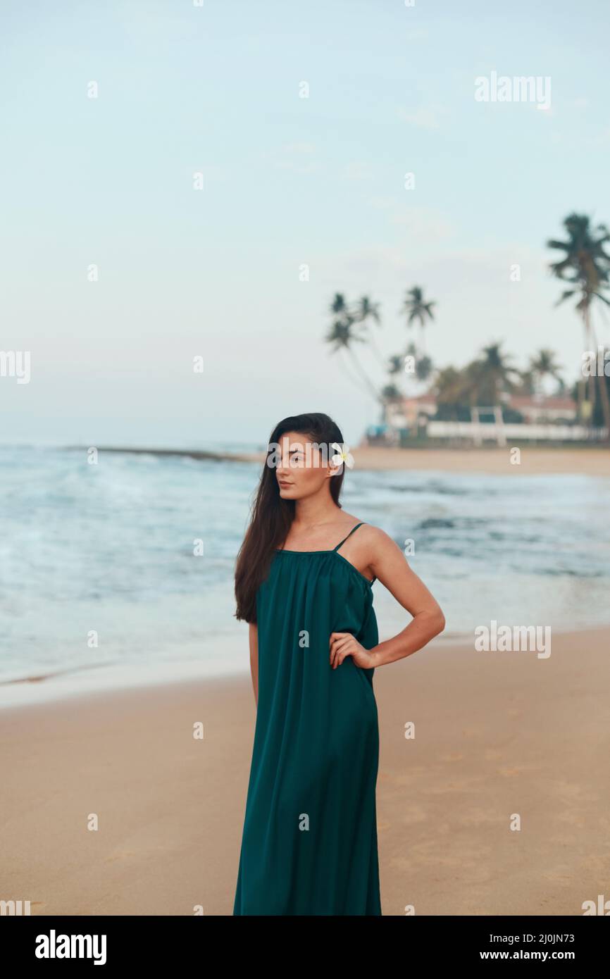 Portrait of beautiful young woman in dress on the beach. Pretty girl on tropical beach. Freedom concept, holiday, beach, sky background. Stock Photo