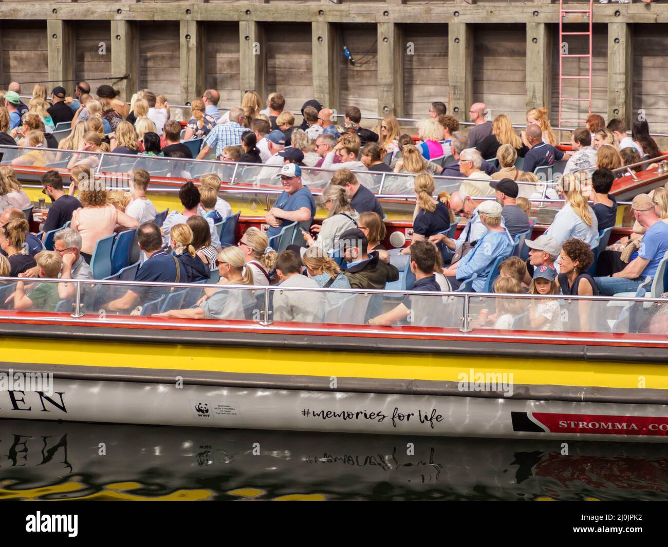 Copenhagen, Denmark - July,  2021: Tourists in the sightseeing tour boat in the Nyhavn canal of New Harbour in the Old Town of Copenhagen. Europe Stock Photo