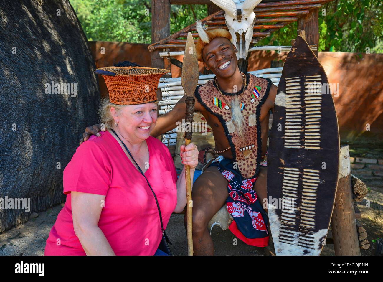 Zulu tribesman with tourist at Motseng Cultural Village, Sun City Resort, Pilanesberg, North West Province, South Africa Stock Photo