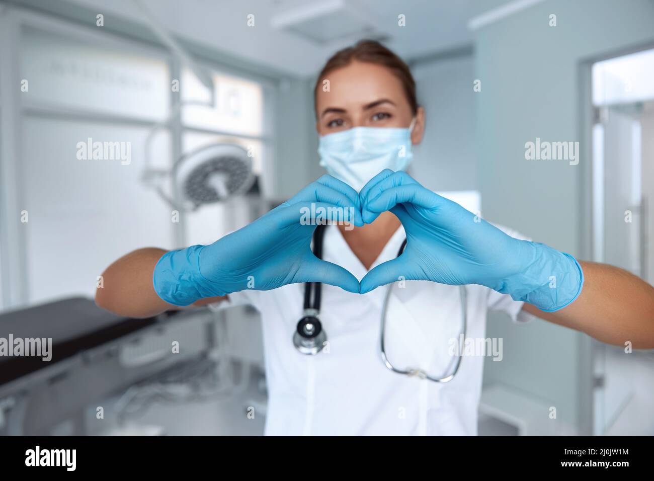 Woman with a medical mask and hands in latex glove shows the symbol of ...