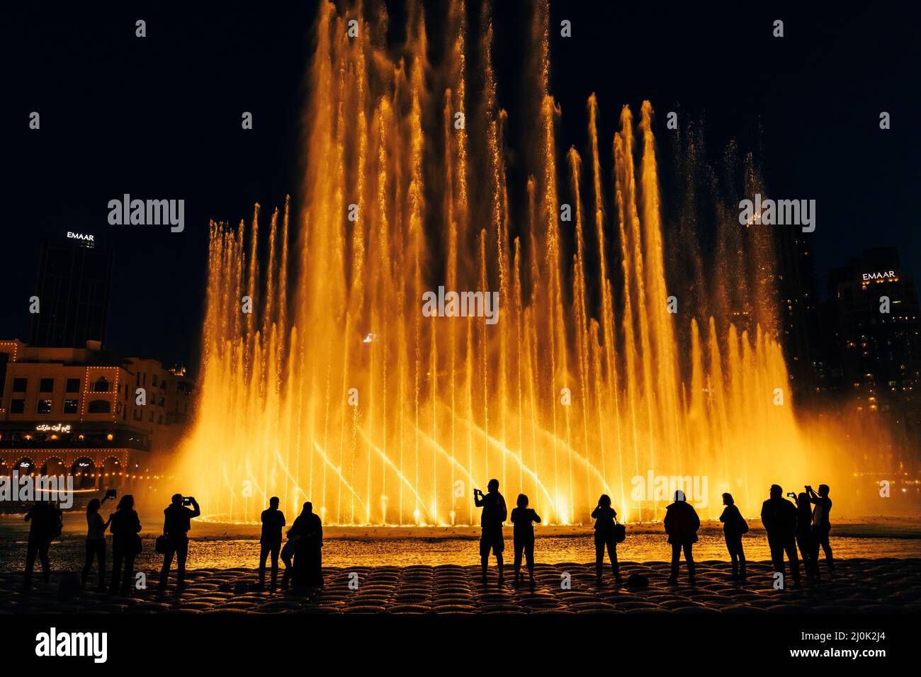 Silhouettes of people enjoying the fountain show in Dubai at night, United Arab Emirates - Stock Image