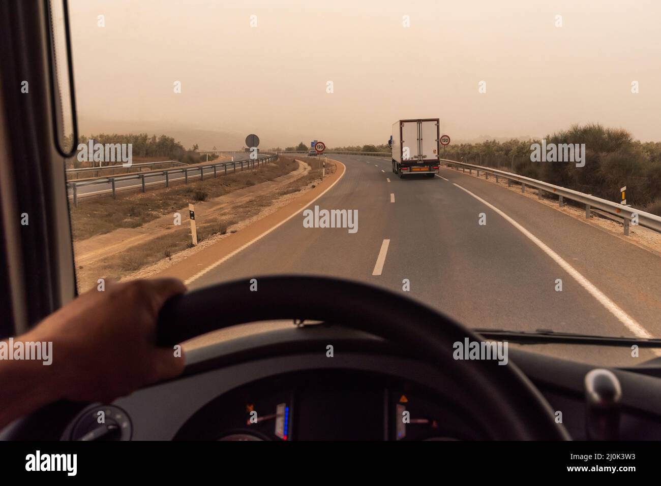 View from the driver's seat of a truck, with a refrigerated trailer driving in front. Stock Photo