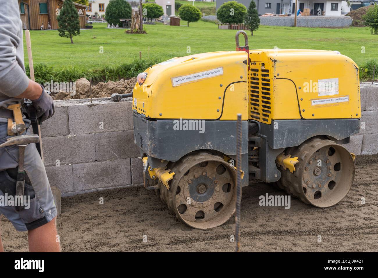 Construction worker on construction site with trench roller to compact the earth - house building Stock Photo