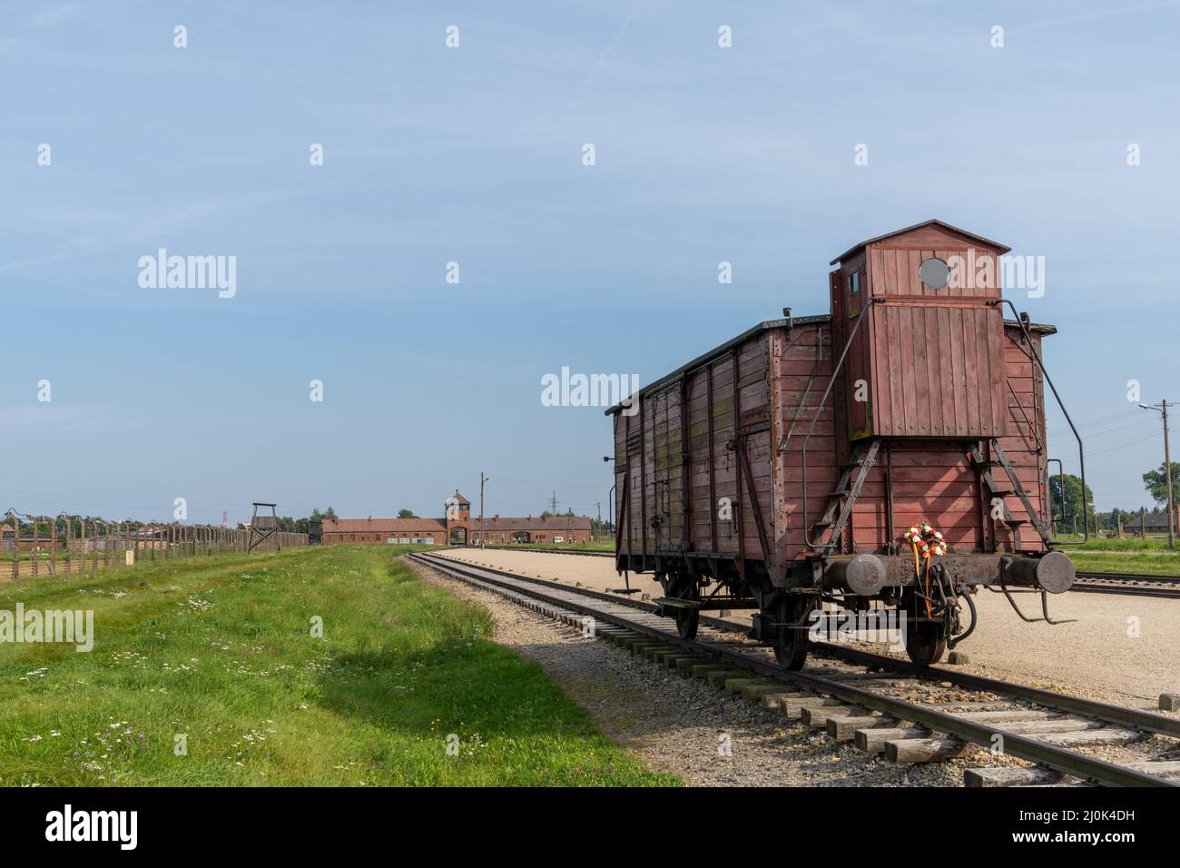 Auschwitz Concentration Camp in Poland with railroad tracks and a wooden carriage for transporting prisoners in the foreground Stock Photo