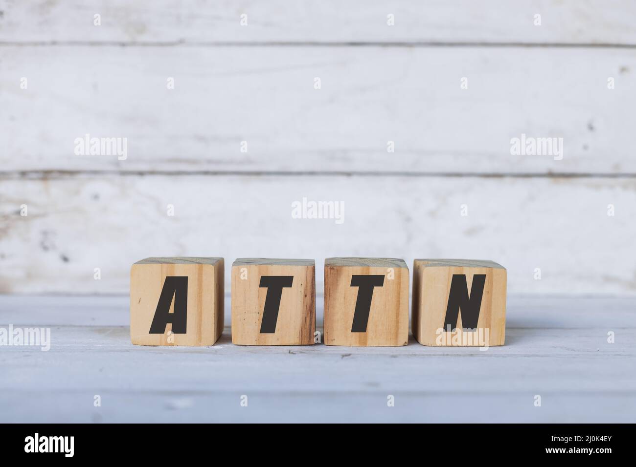 ATTN concept written on wooden cubes or blocks, on white wooden background. Stock Photo