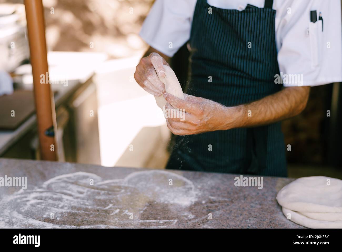 Chef's hands close-up. Prepares the dough for pizza, rolls out in round shapes with his hands. Stock Photo