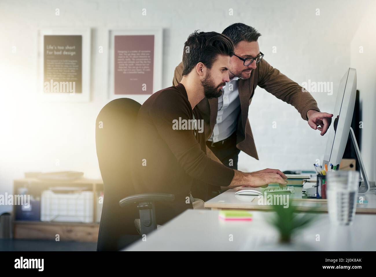 Working together brings out the best in us. Shot of two designers discussing something on a computer screen. Stock Photo