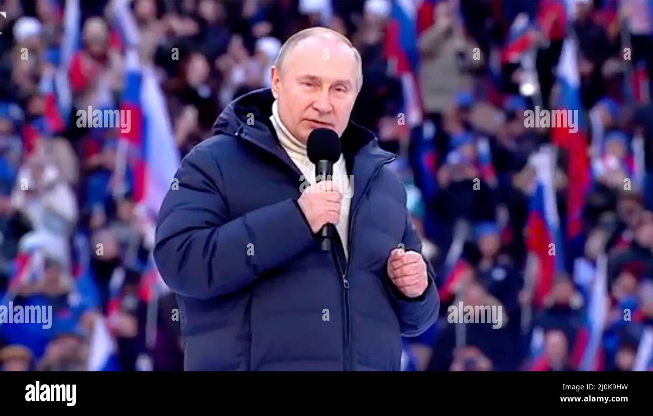 VLADIMIR PUTIN addresses a rally in Moscow on18 March 20223 to celebrate  the eighth anniversary of the annexation of Crimea. on Friday 18 March. He is wearing a white turtleneck sweater  from Italian company Kiton and a puffa jacket  by Loro Piana.Photo: Kremlin.ru Stock Photo