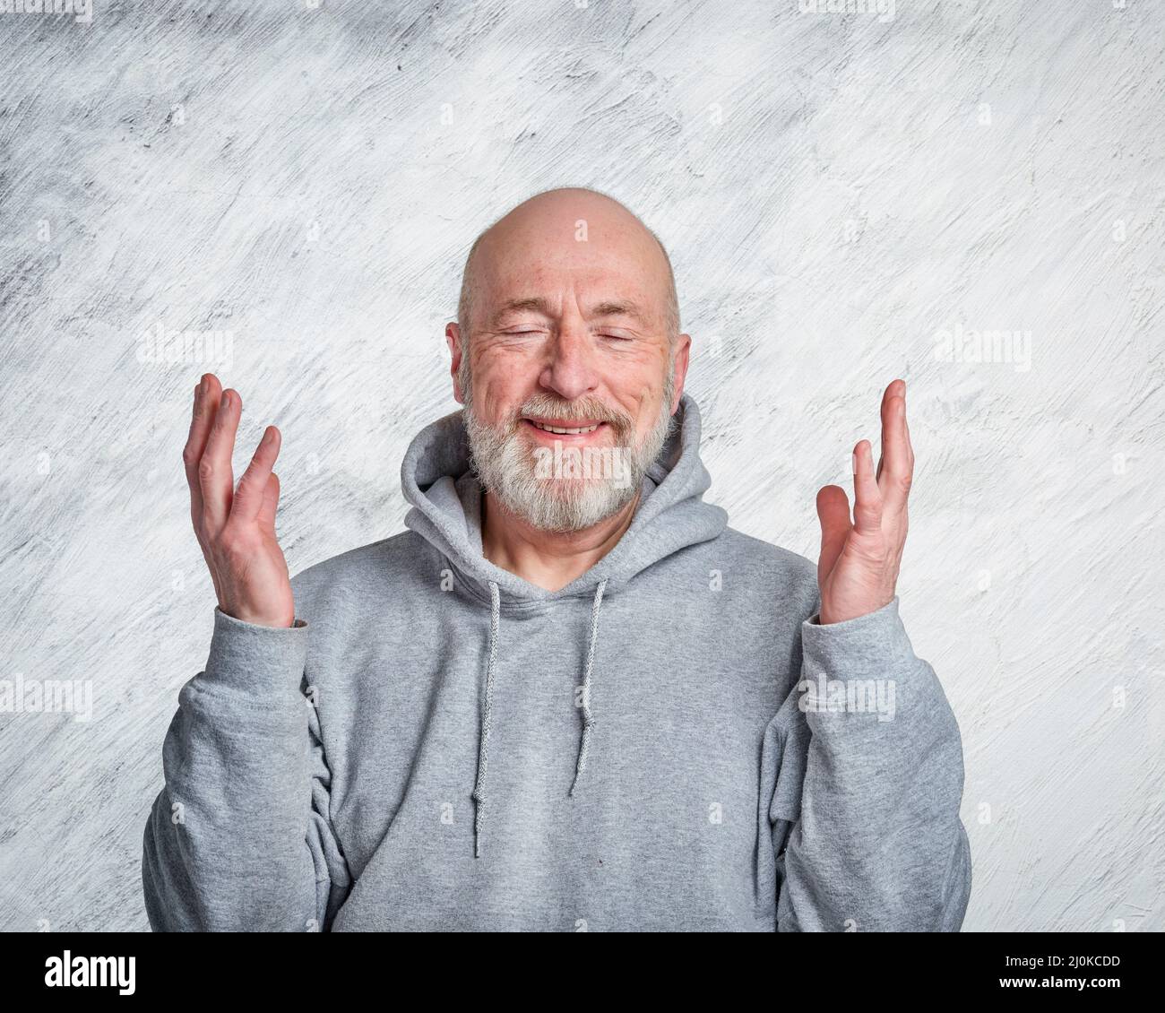 casual, portrait of happy and smiling gesticulating senior man wearing hooded sweatshirt Stock Photo
