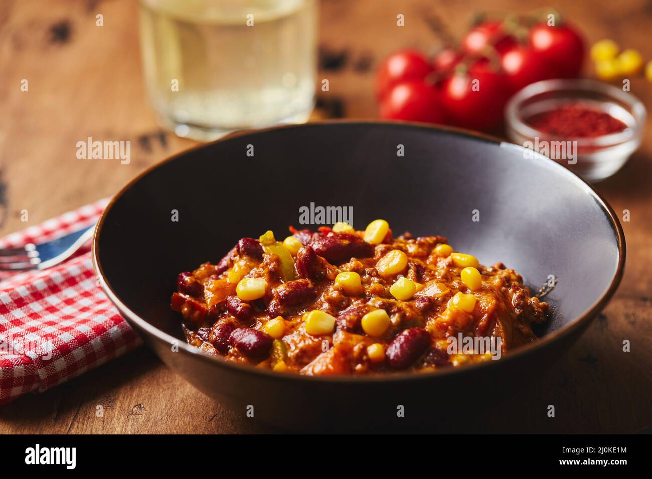 Chili Con Carne with ground beef, beans and corn in dark bowl on wooden ...