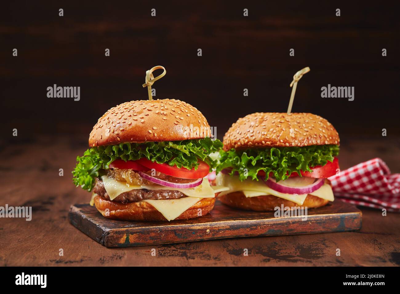 Two homemade burgers with beef, cheese and onion marmalade on a wooden board. Fast food concept, american food Stock Photo