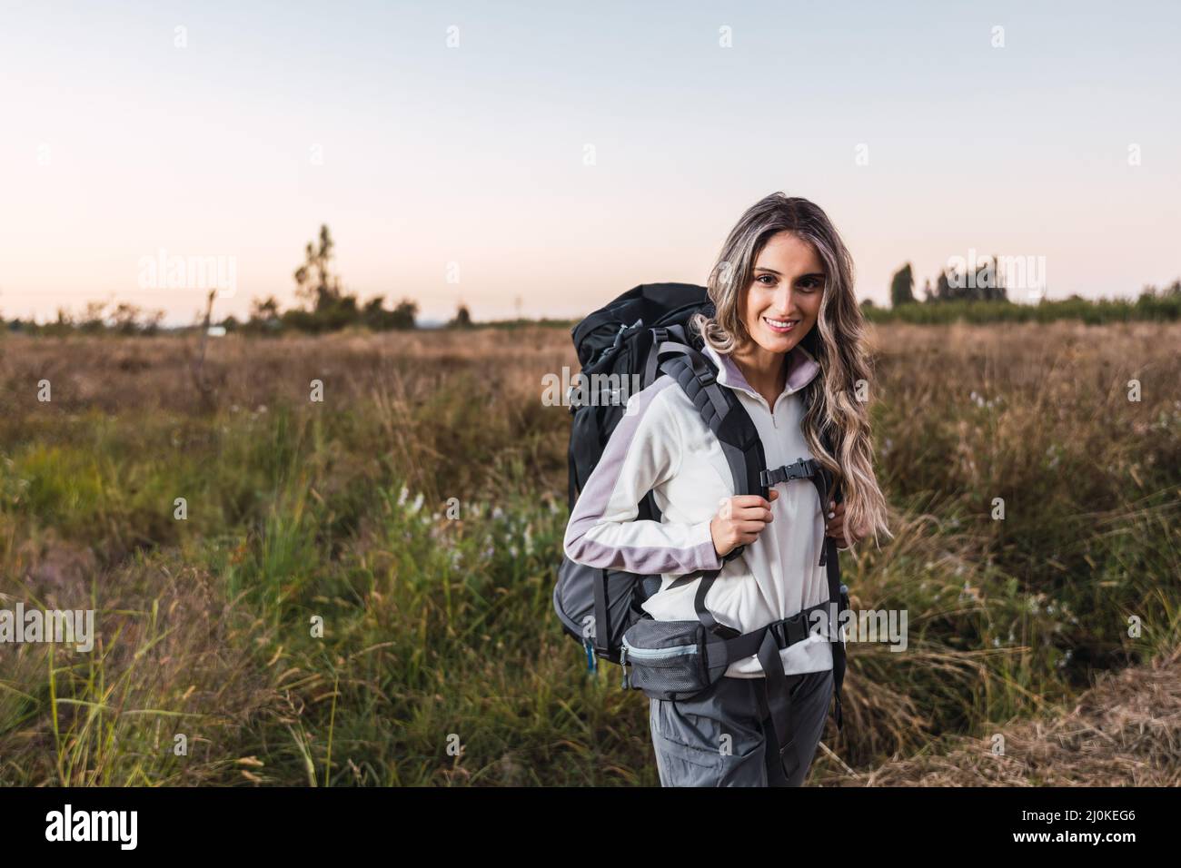 Young woman with a backpack on, ready to start hiking. Teleworking. Digital nomad Stock Photo