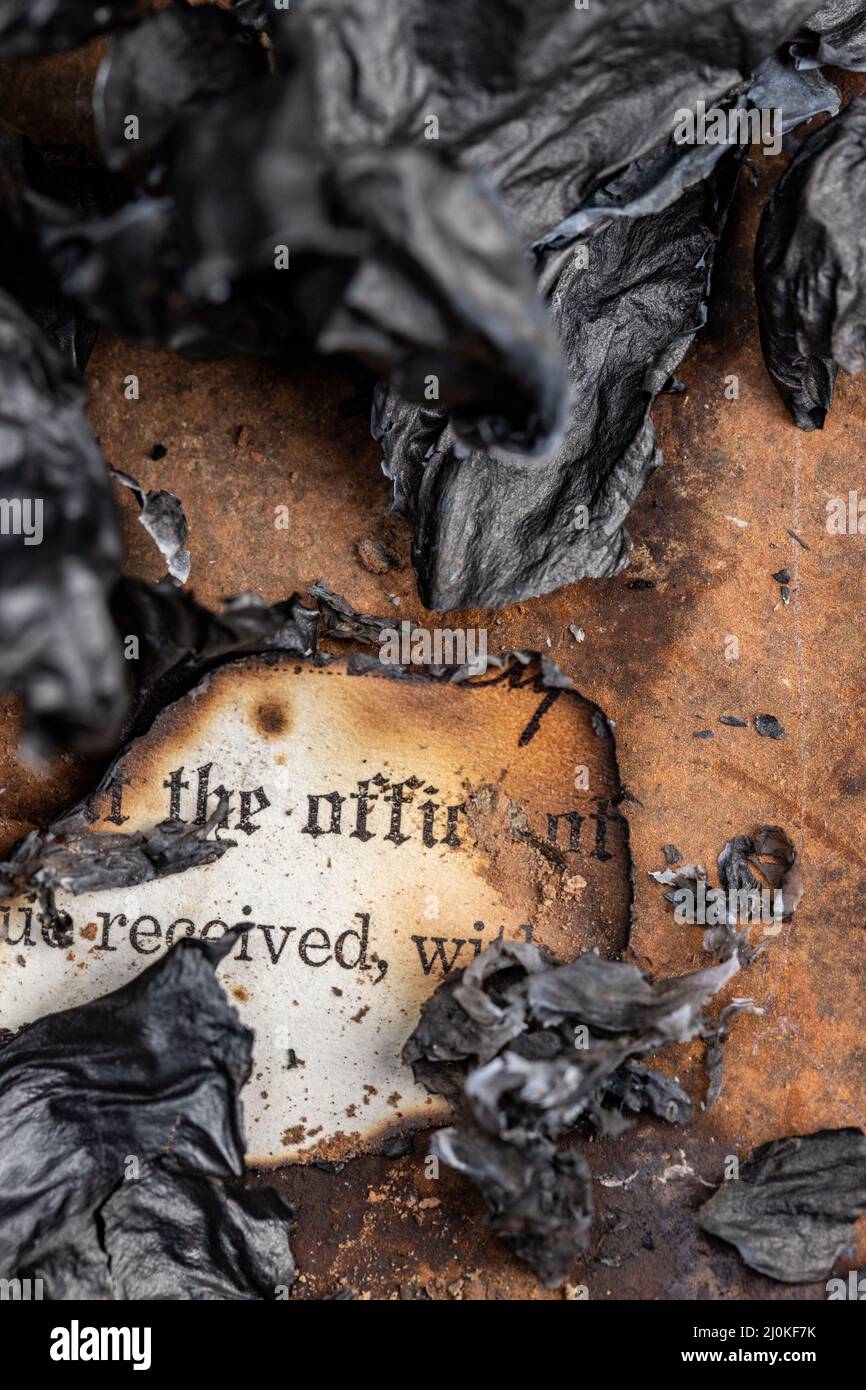 Old burned paperwork surrounded by burnt paper ashes Stock Photo