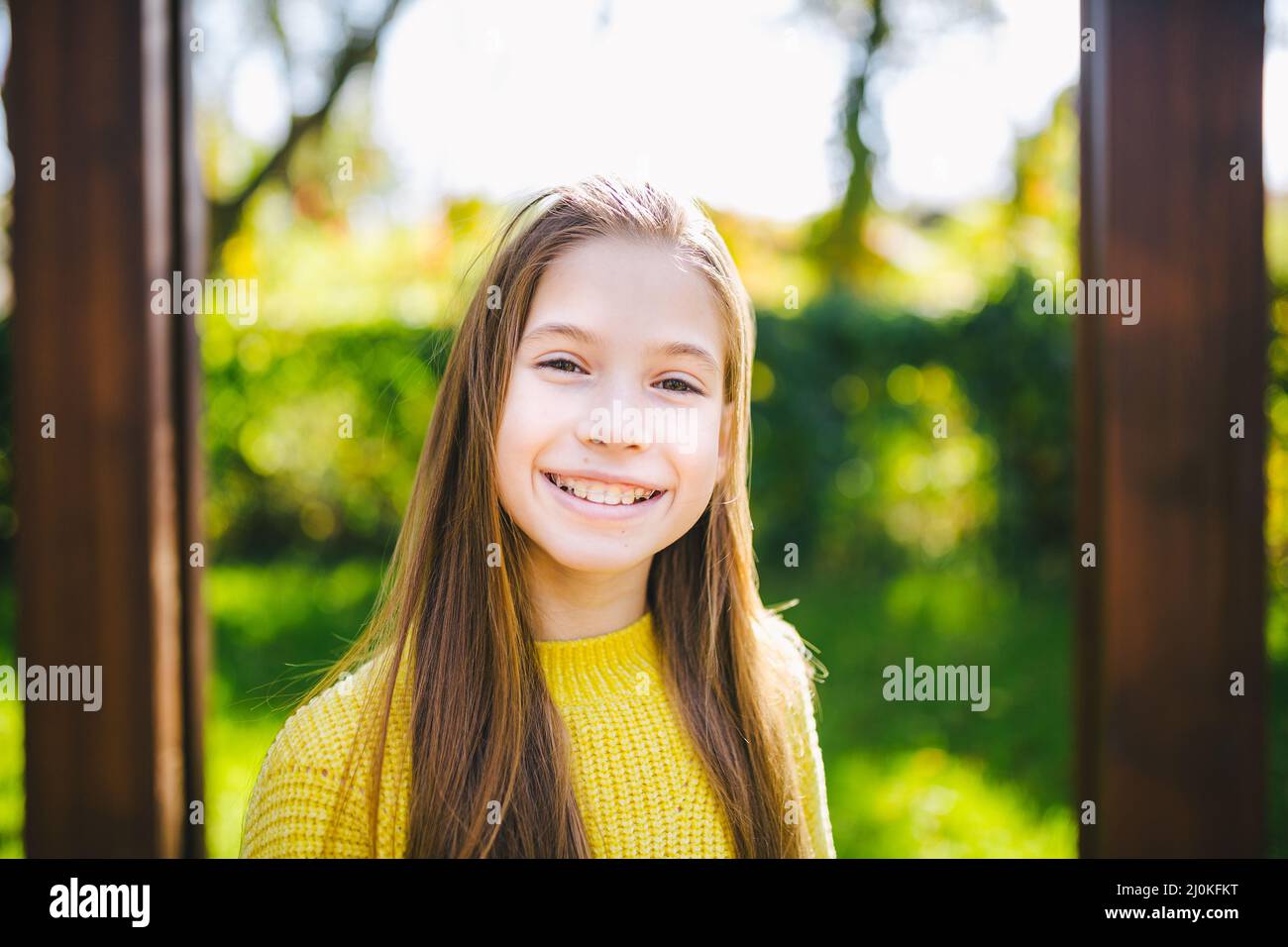 Pretty teenage girl wearing braces smiling cheerfully dressed in bright yellow clothes outdoors. Cute and happy teen girl with b Stock Photo