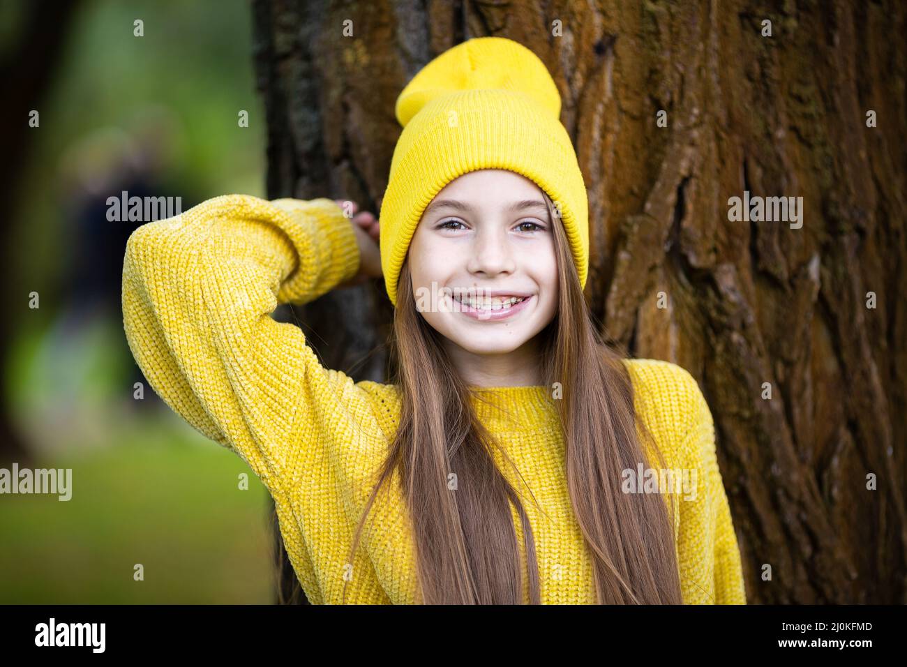 Cute and happy teen girl with braces smiling to camera in yellow clothes in park. Concept of dentist and orthodontist. Pretty te Stock Photo