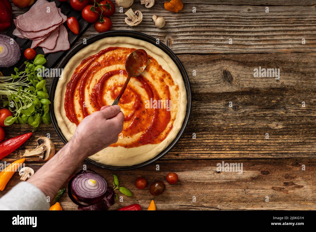 Raw delicious pizza dough with red souce on the wooden table Stock Photo