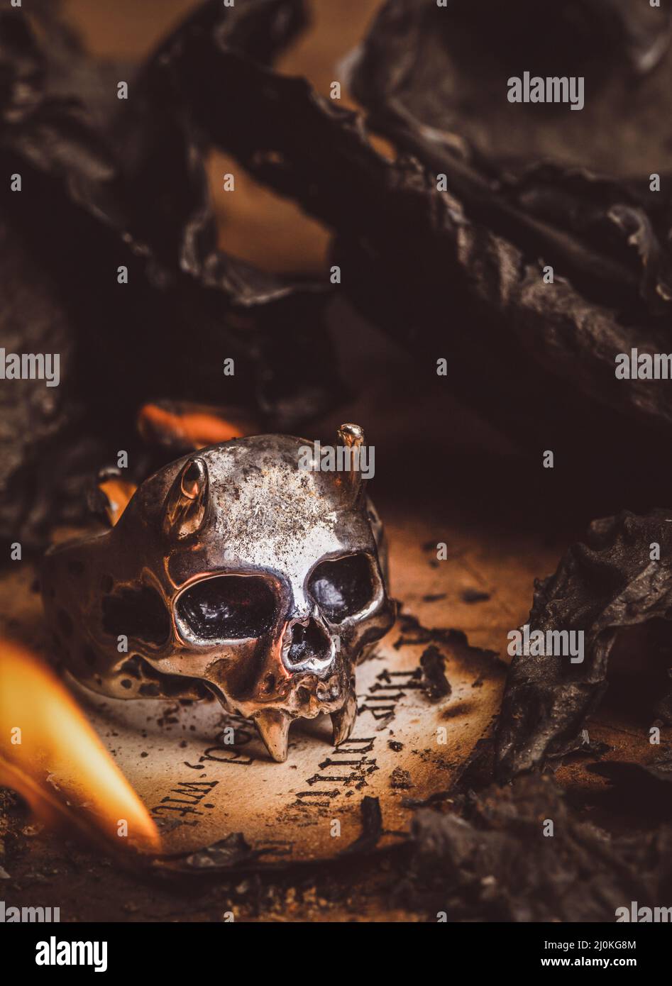 Old Skull Ring surrounded by burnt paper ashes Stock Photo