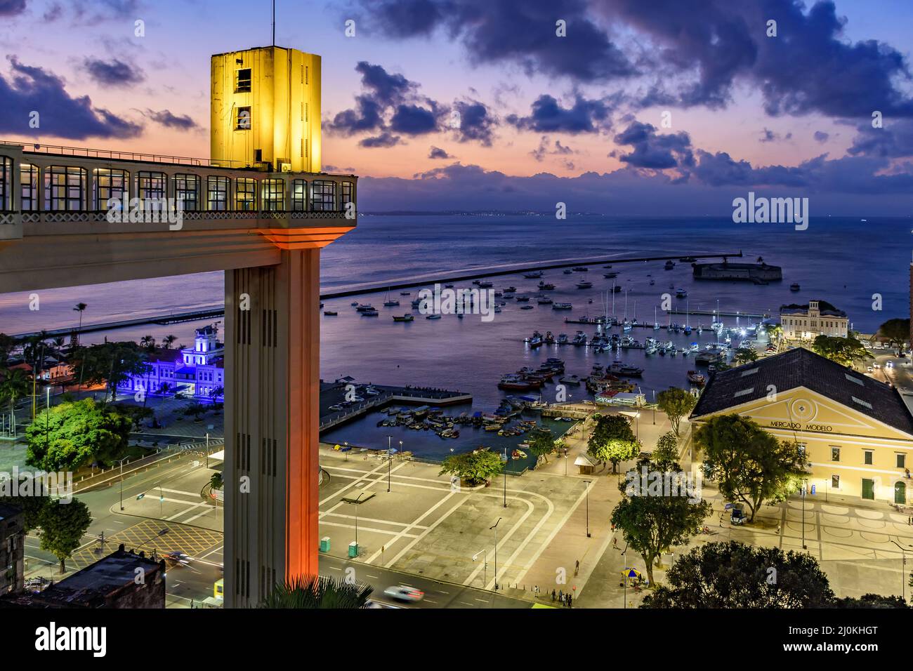 Lacerda elevator illuminated at dusk and with the sea and boats in the background Stock Photo